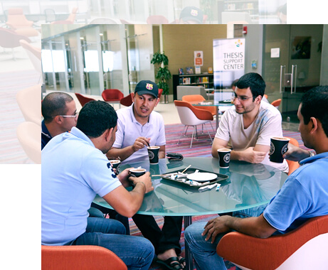 Five KAUST students talk around a table.